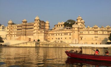 red and white boat on body of water near beige concrete building during daytime