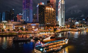 a boat floating on top of a river next to tall buildings